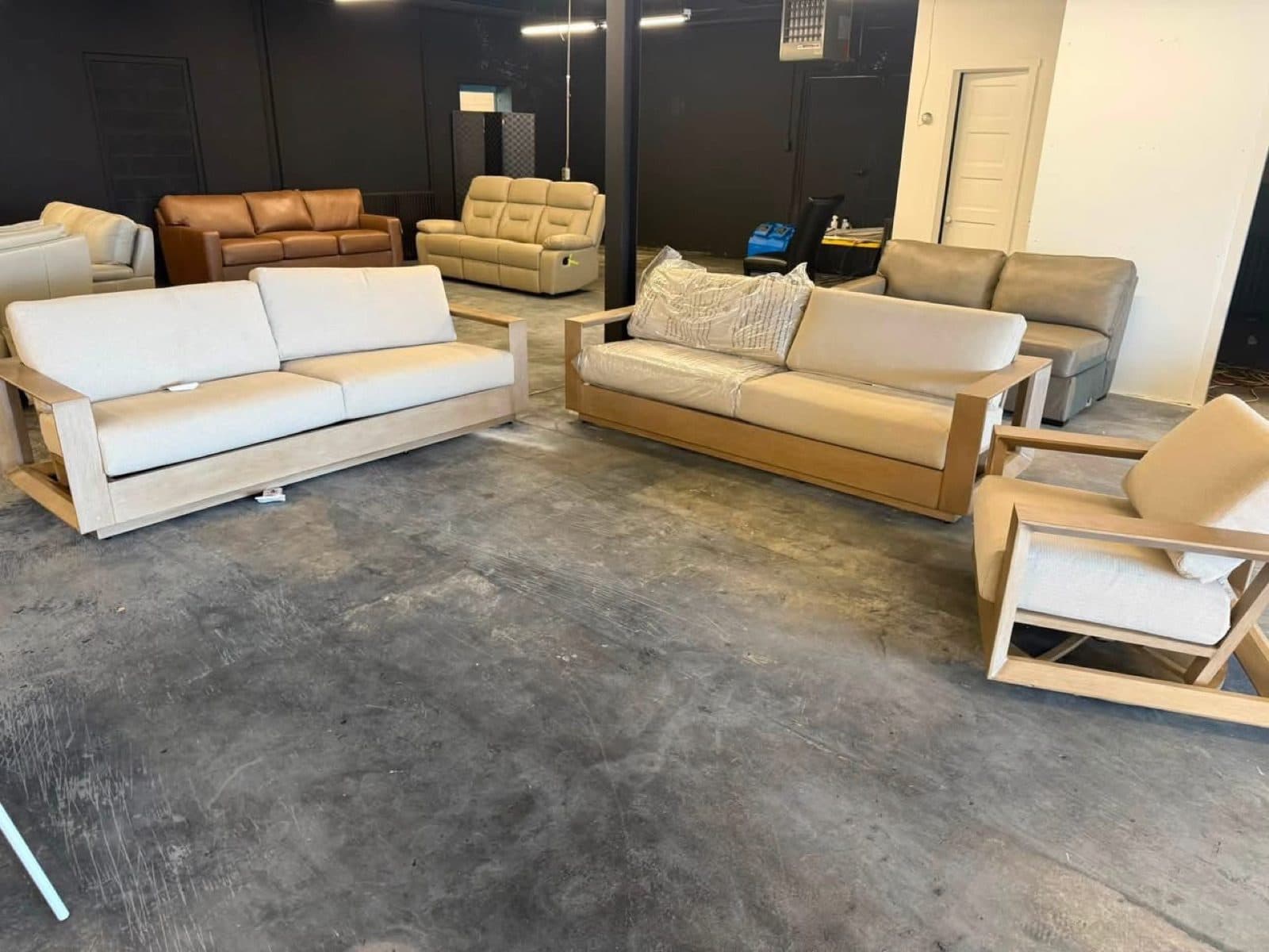 Three piece wood frame outdoor sofa, loveseat, and chair set on the showroom floor