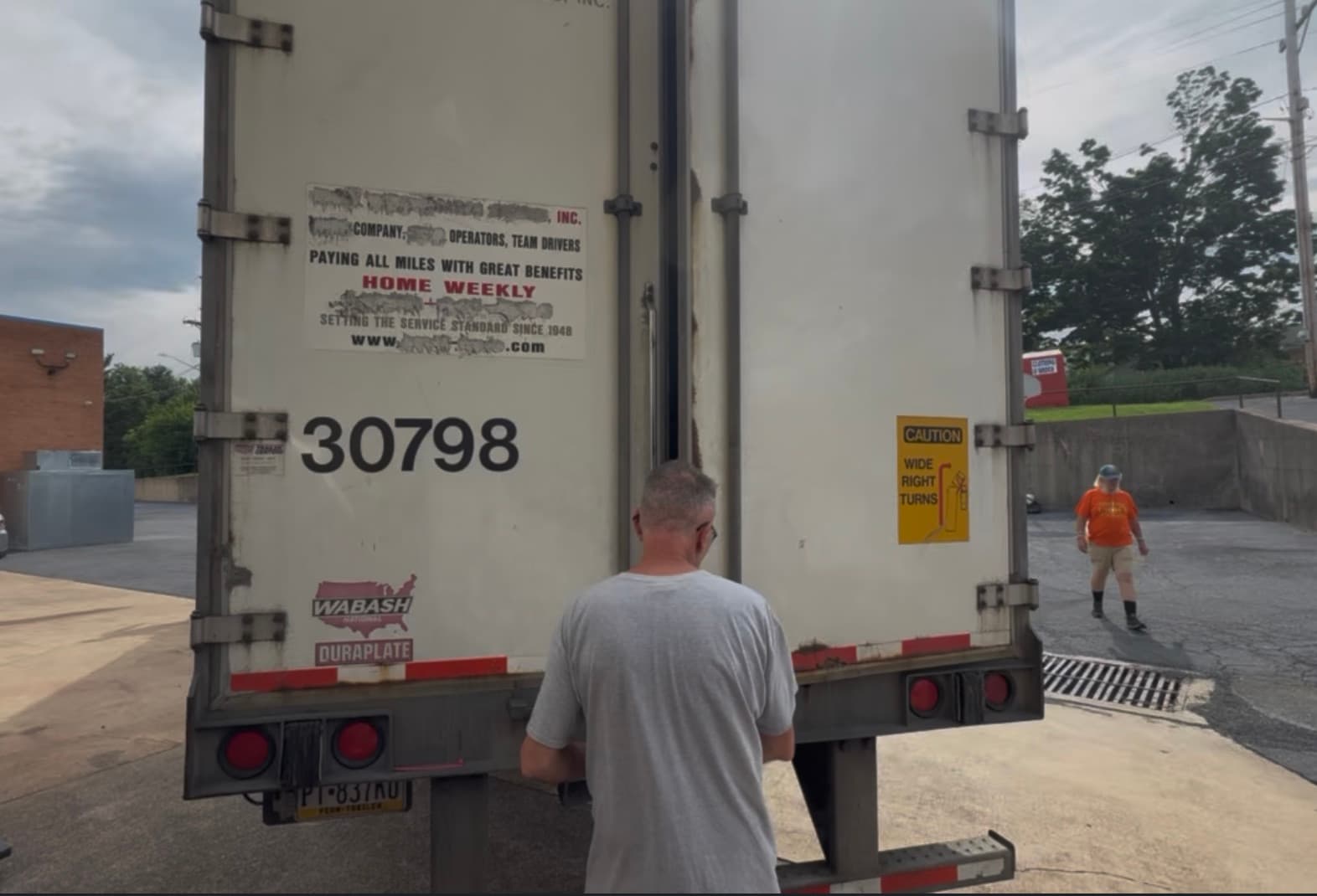 Semi trailer backed up to the warehouse with the rear doors being opened for unloading